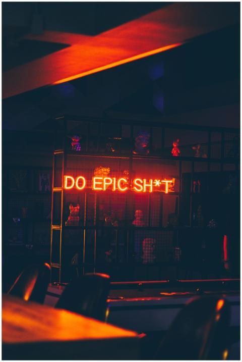 Moody bar interior with neon text 'Do Epic Sh*t' c