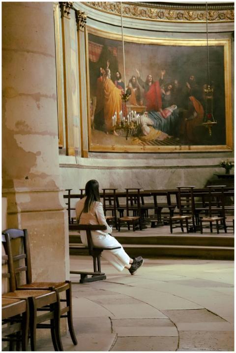 A woman contemplates art in a historic Parisian ch