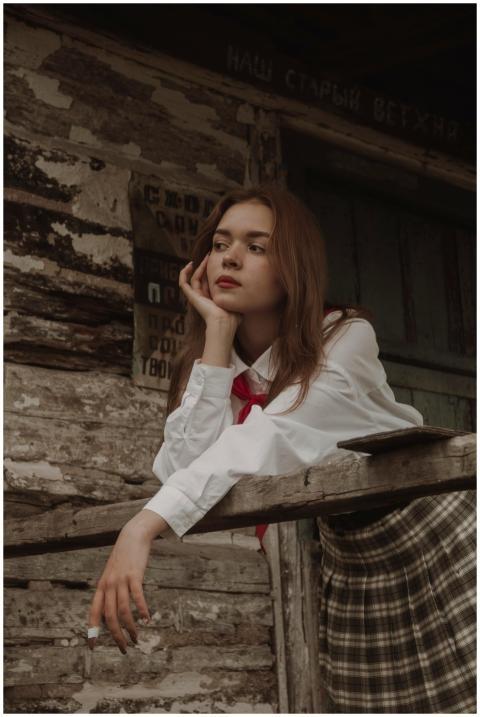 Young woman in vintage attire leaning on a wooden