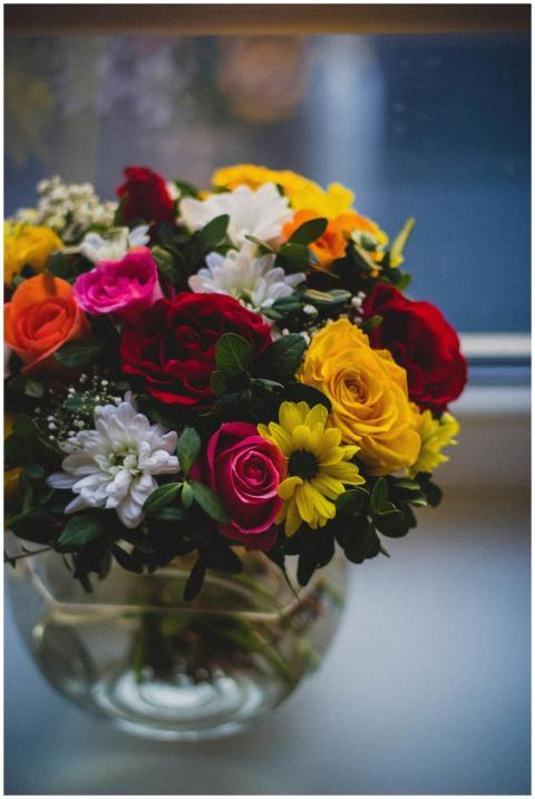 A colorful bouquet of roses and daisies in a glass