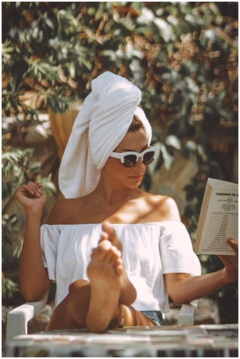 A stylish woman reads outdoors in summer, exuding