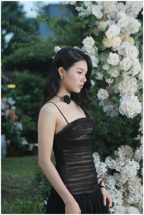 A sophisticated woman in a black dress standing be