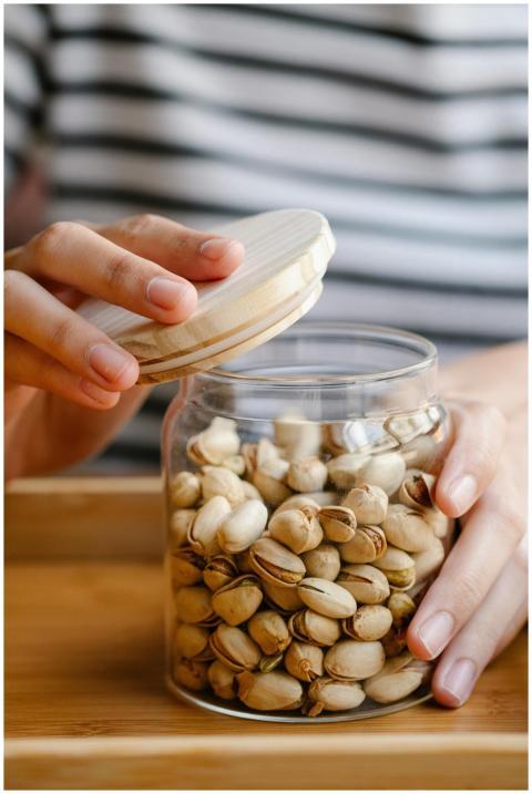 Close-up of hands holding a glass jar of pistachio