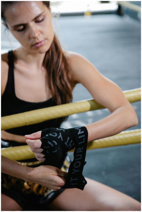 Focused woman wrapping hands before a boxing worko