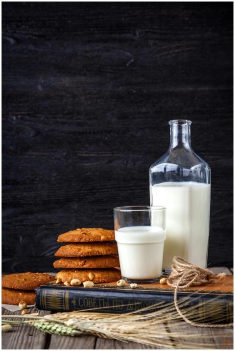 Glass of milk with stack of cookies, book, and bot