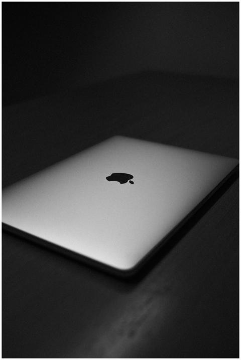 A sleek silver laptop lies closed on a dark surfac