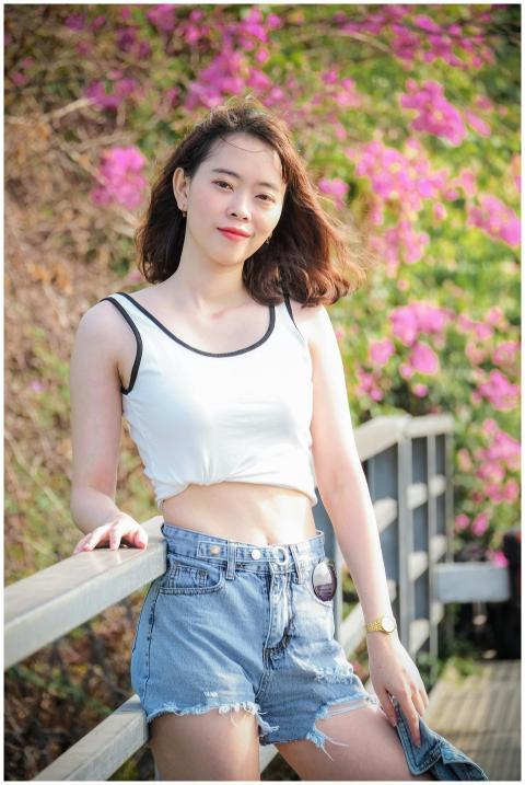 Asian woman in casual attire smiling in front of v