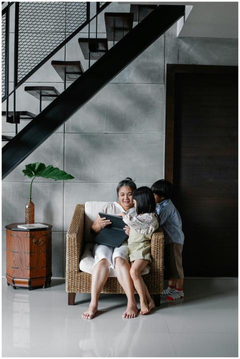 Asian woman sitting with kids on armchair and brow