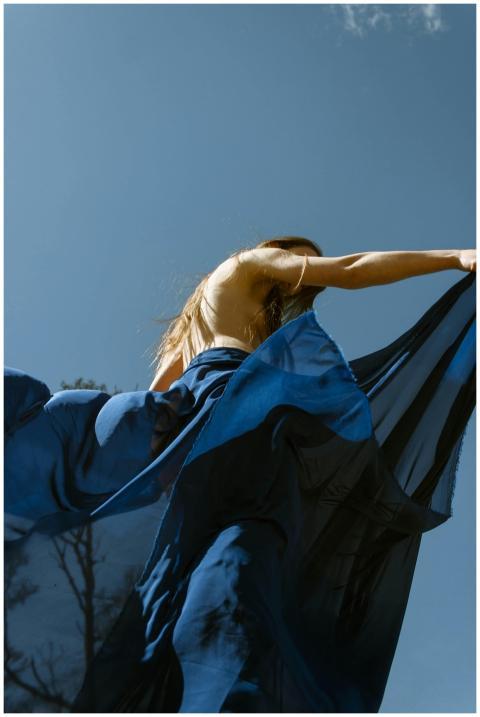 A model in a flowing blue dress poses gracefully a