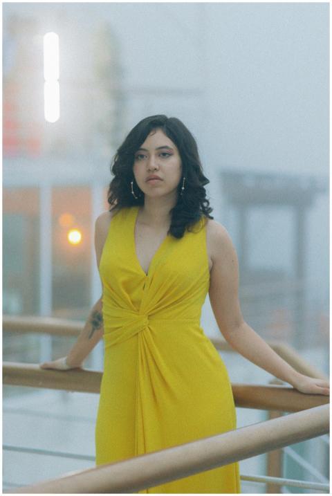 Stylish woman in a yellow dress poses calmly on a