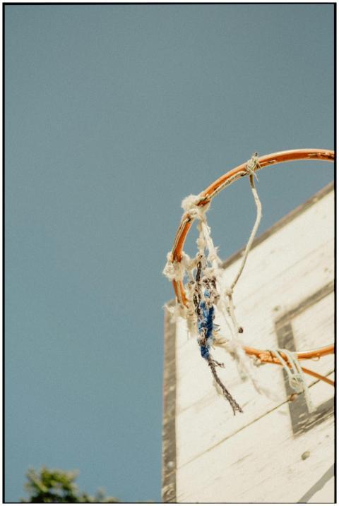 Old basketball hoop with frayed net under a clear