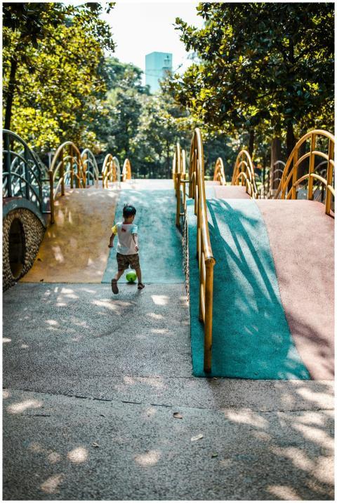 A young boy plays with a ball on a vibrant playgro
