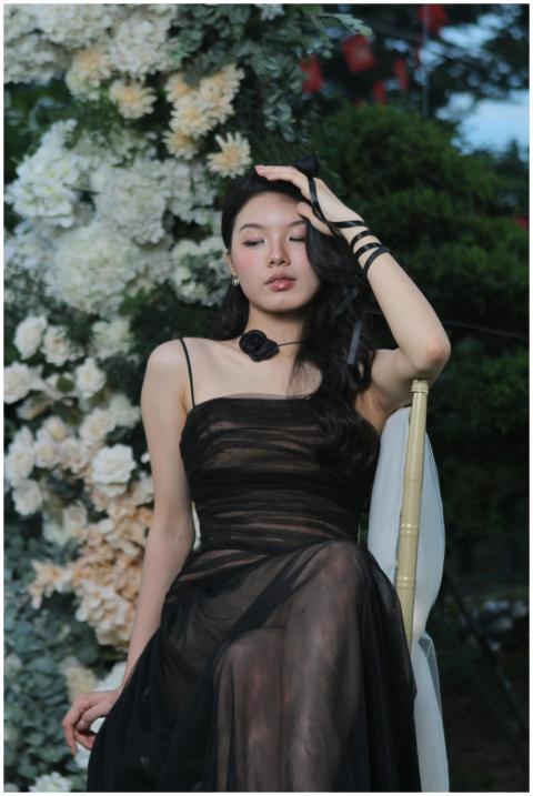 A woman in a black dress poses gracefully against