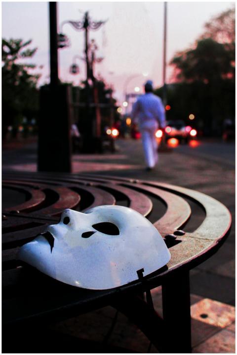 A solitary white mask on a circular bench at dawn