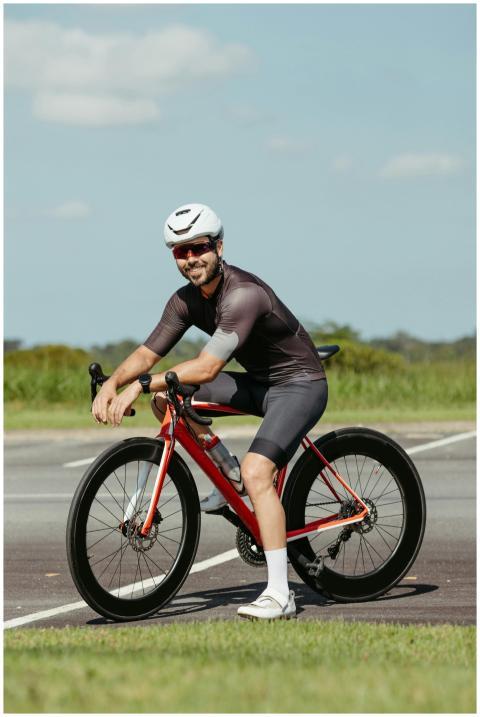 A cyclist in modern gear poses with his red bike o