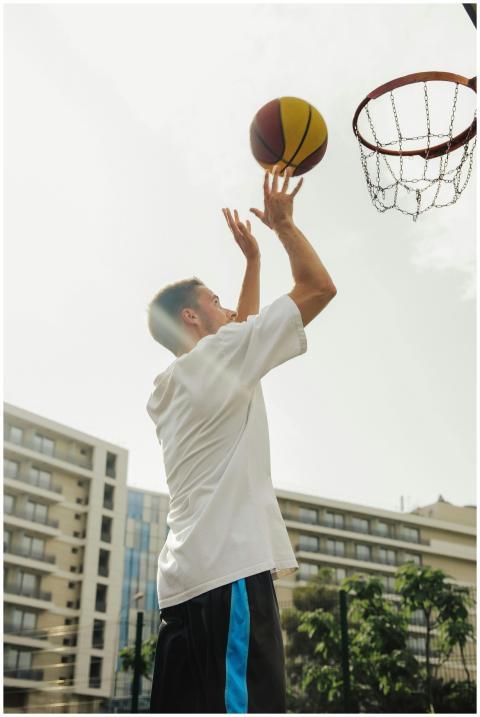 A young man in a white shirt shooting basketball o