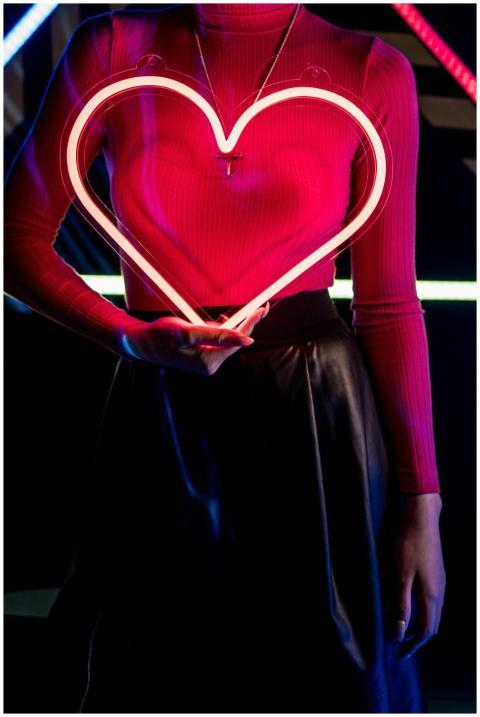 A woman holds a neon heart under vibrant cyberpunk