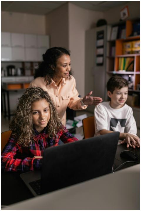 A teacher assisting students with laptop learning