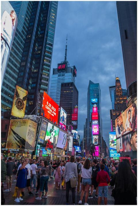 Crowded Times Square in New York City at dusk, fea