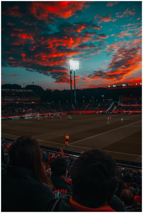 Dramatic sunset over a lively soccer game in a lar