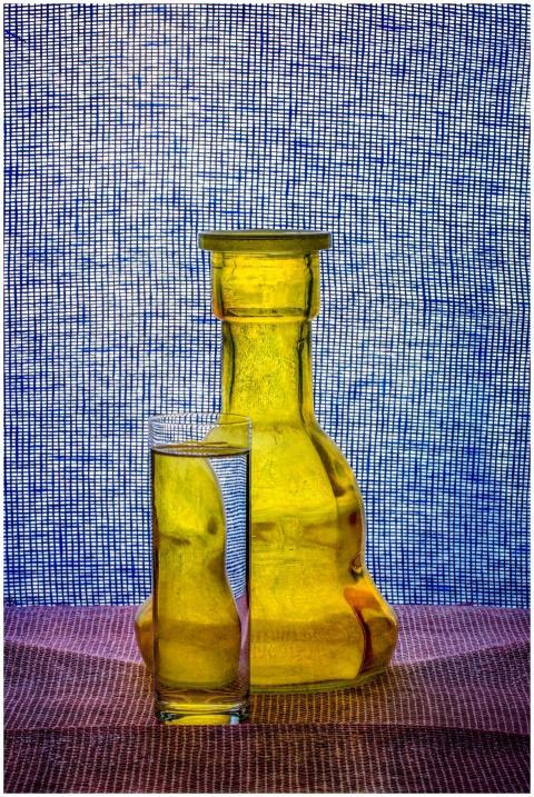 A vibrant still life of a glass and bottle with a