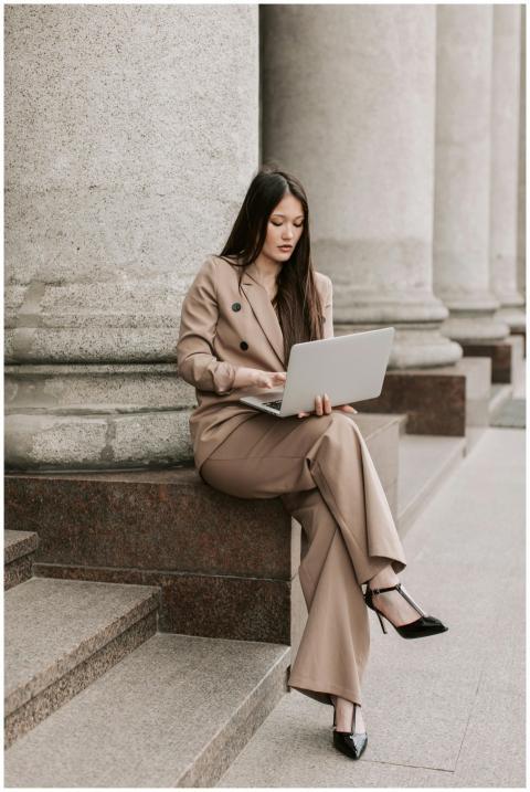 Stylish woman in brown suit working on laptop outs