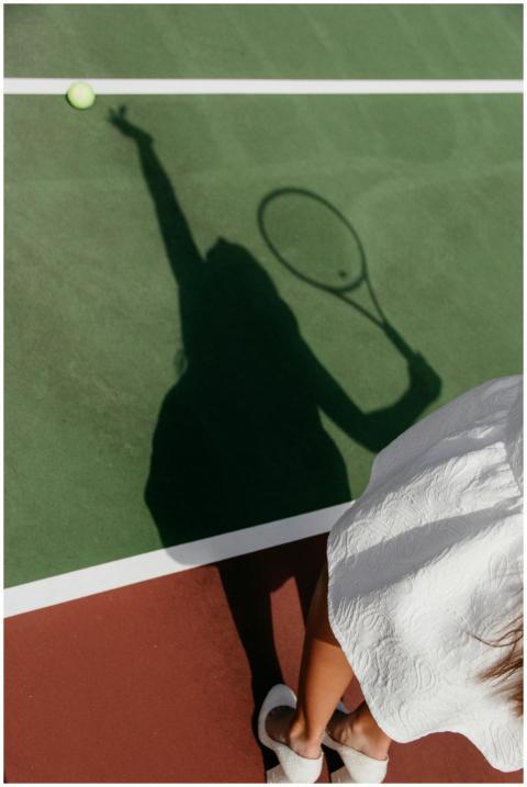 Shadow of a tennis player with racket on a green c
