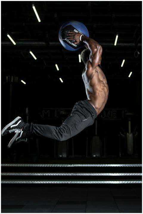 Muscular athlete performing a high jump with a med