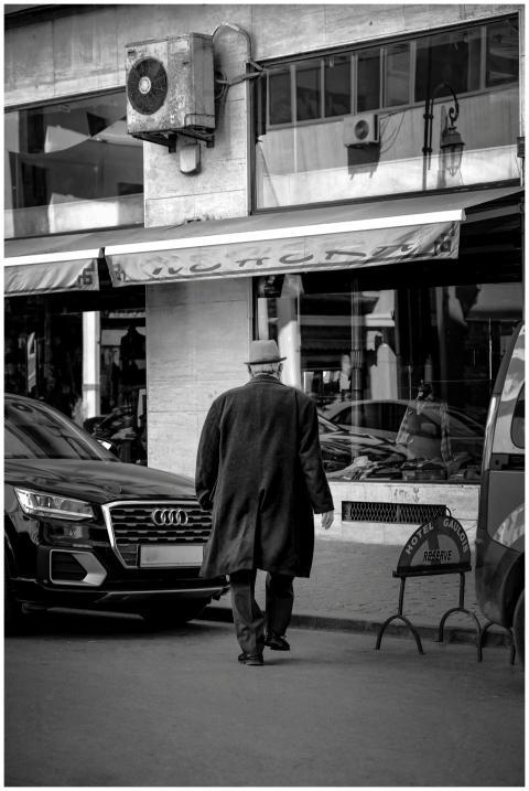 A solitary man walks down a city street surrounded