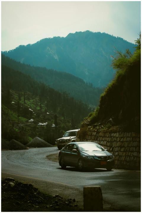 Cars navigating a winding road through lush mounta