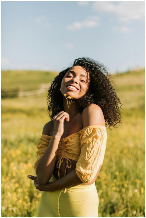A joyful woman in a yellow outfit posing in a sunn
