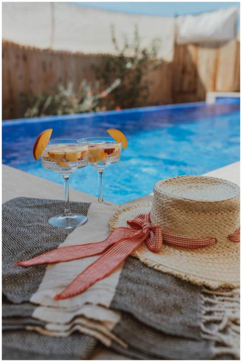 Close-up of cocktails and a straw hat by a vibrant