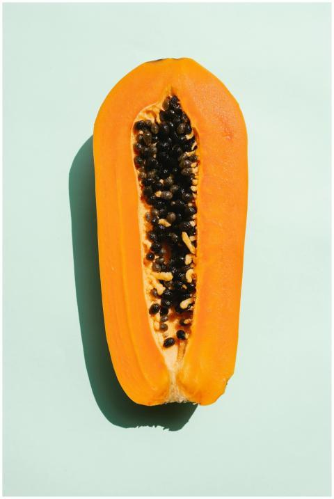 Bright halved ripe papaya on a light mint backgrou