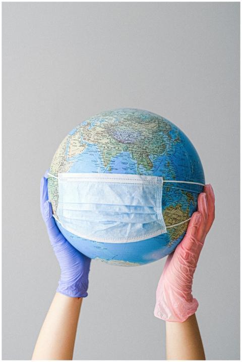 Hands in gloves holding a globe with a mask, symbo