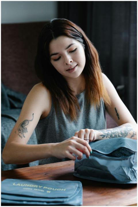 Tattooed woman with tattoos packing laundry pouche