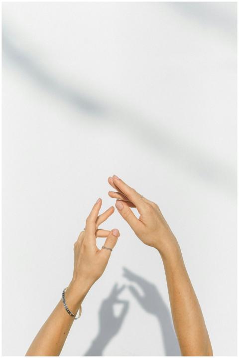 Elegant hands casting shadows on a bright white wa