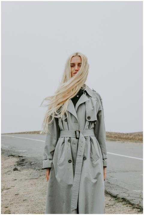 A fashionable woman with long hair poses in a gray