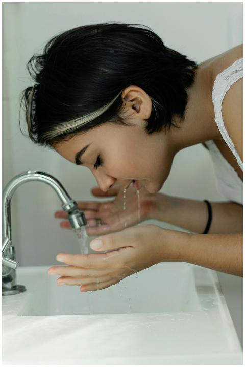 A woman with short hair gently washes her face at
