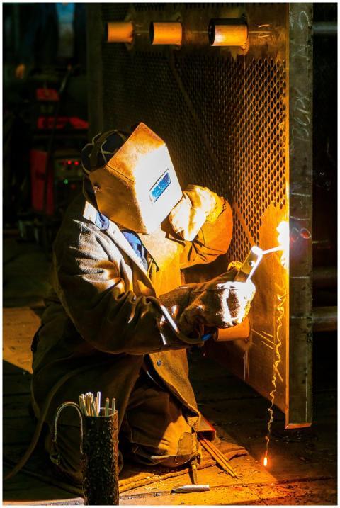 A skilled welder works with a torch in an industri