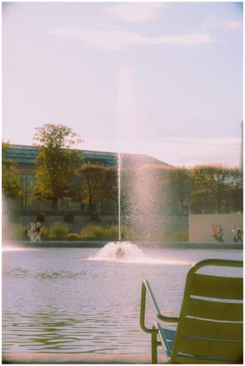 A peaceful fountain in a Paris park with people st