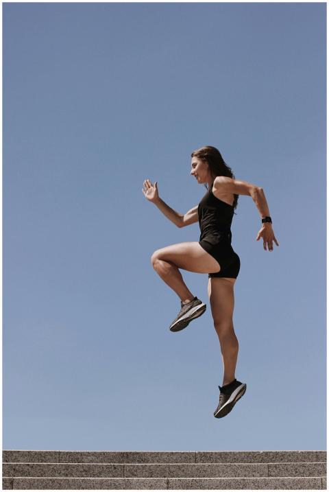 A woman in athletic wear energetically leaps up st