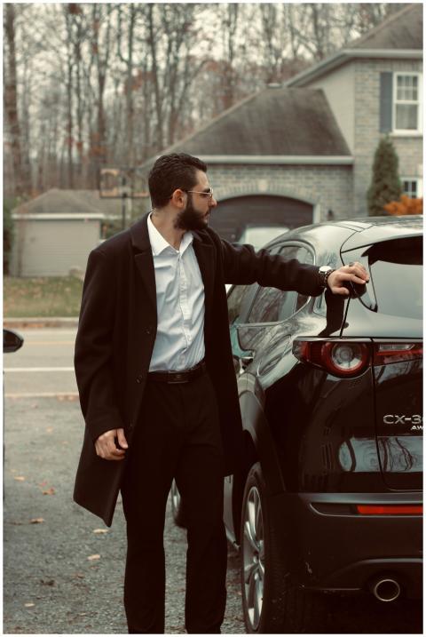Fashionable man in a coat standing by his car in a