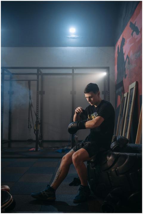 A male boxer takes a break in a dimly lit gym, pre