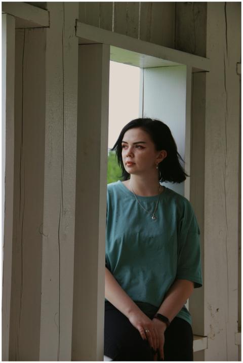 A woman sits thoughtfully by a window, contemplati