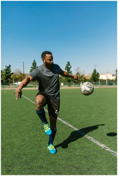 An athlete practicing soccer skills on a green fie