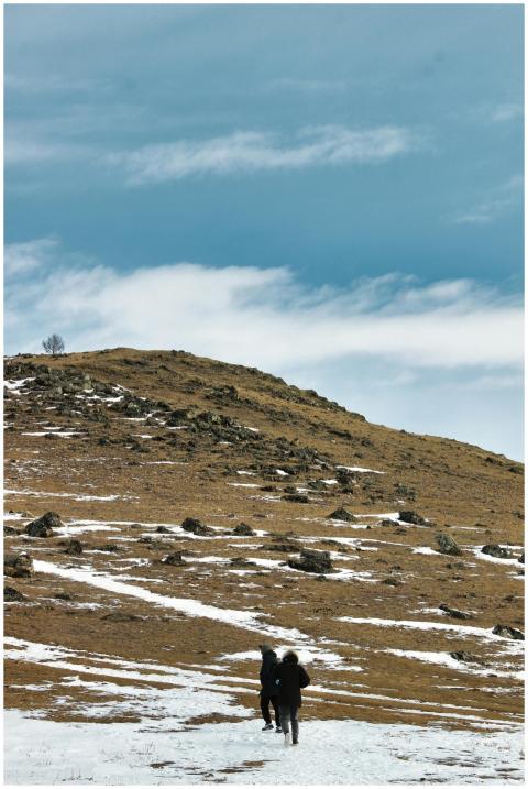 Two people hiking on a snow-covered hillside under