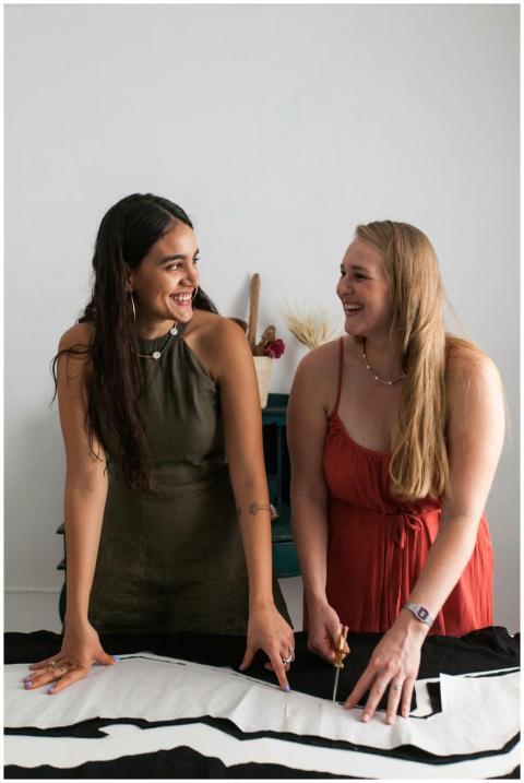 Two women fashion designers smiling and collaborat
