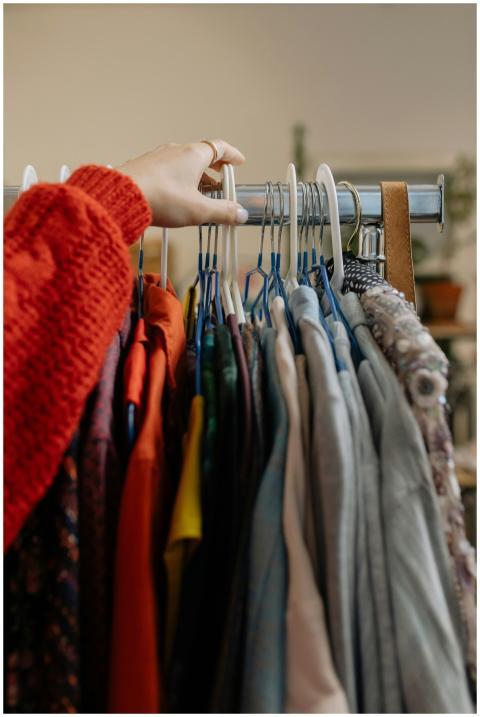 A woman browsing garments on hangers in a retail c
