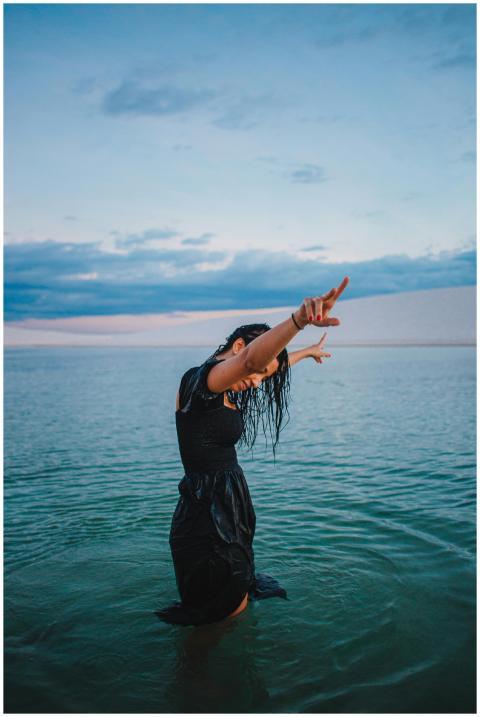 Woman in a black dress standing in water, posing w