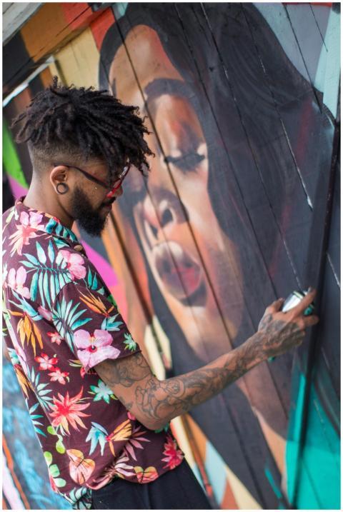 A street artist paints a vibrant mural outdoors, s